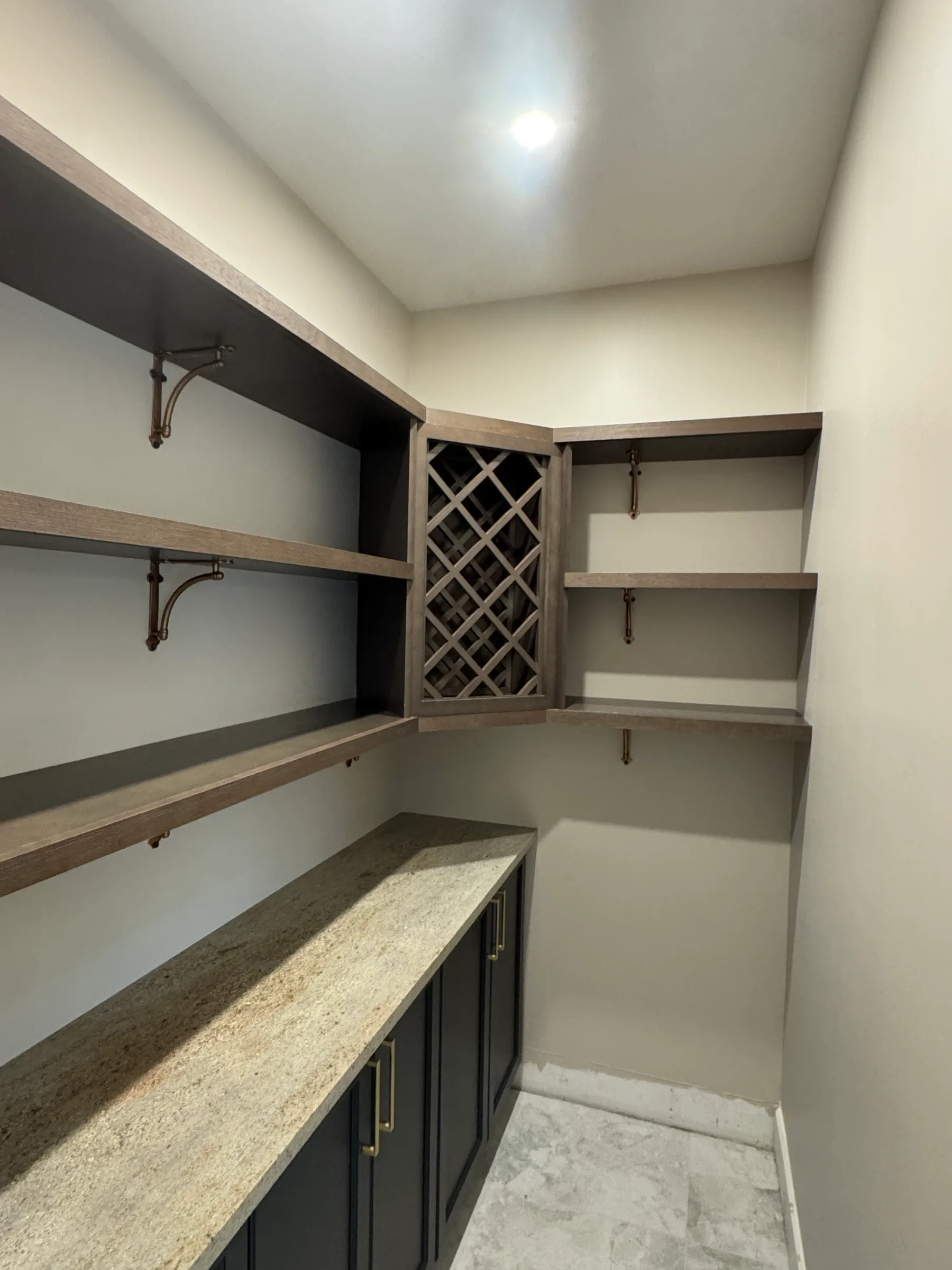 Built-in wine lattice with open shelving on brass brackets